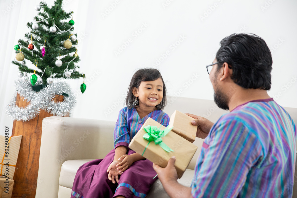 father and daughter sitting together and open the present in christmast day father and daughter sitting together and open the present in christmast day