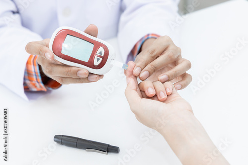Фотография Pharmacist in pharmacy determines blood glucose level for insulin determination in patient, Sample blood analysis to determine blood group