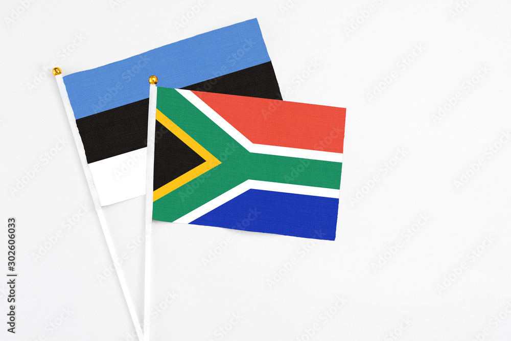 Fototapeta premium South Africa and Estonia stick flags on white background. High quality fabric, miniature national flag. Peaceful global concept.White floor for copy space.