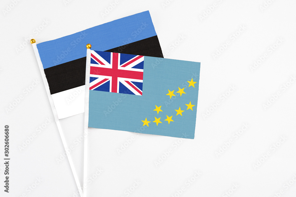 Fototapeta premium Tuvalu and Estonia stick flags on white background. High quality fabric, miniature national flag. Peaceful global concept.White floor for copy space.