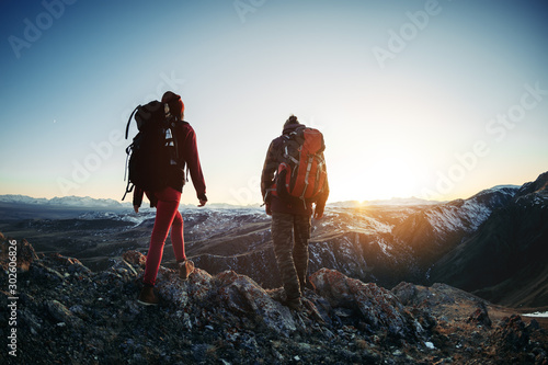 Two hikers walk sunset mountains