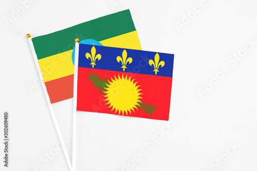 Guadeloupe and Ethiopia stick flags on white background. High quality fabric, miniature national flag. Peaceful global concept.White floor for copy space. photo