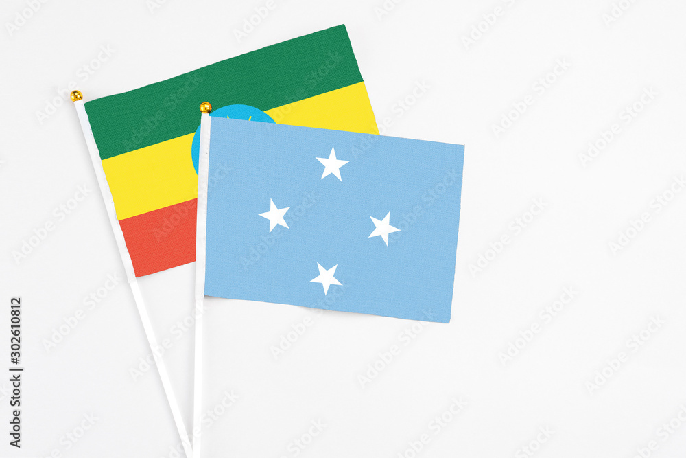 Naklejka premium Micronesia and Ethiopia stick flags on white background. High quality fabric, miniature national flag. Peaceful global concept.White floor for copy space.