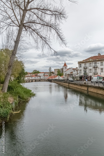 View of a river on Tomar city downtown, vegetation and buildings on banks, Portugal