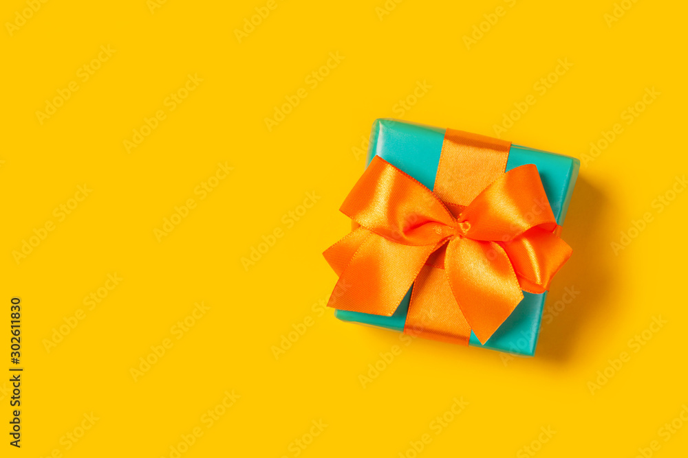 Stylish gift on a trendy orange background. Copy space. Present for St. Valentine's day, engagements, Mother's Day, birthday, New Year, Christmas, holidays Stylish gift on a trendy orange background. Copy space. Present for St. Valentine's day, engagements, Mother's Day, birthday, New Year, Christmas, holidays