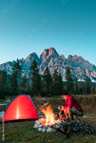 Man Sitting by Campfire and Wild Camping in Mountains. Adventure Concept