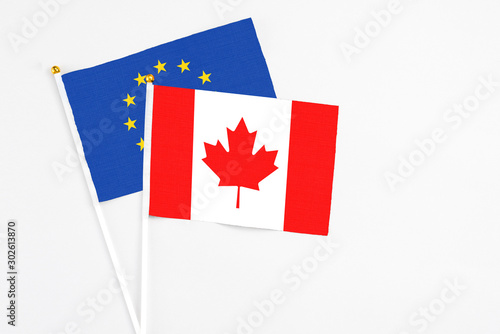 Canada and European Union stick flags on white background. High quality fabric, miniature national flag. Peaceful global concept.White floor for copy space.