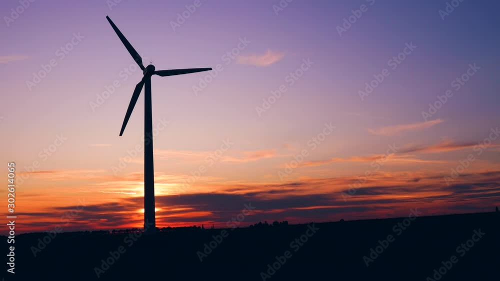 Windmill for electric power production at sunset sky in a field Windmill for electric power production at sunset sky in a field