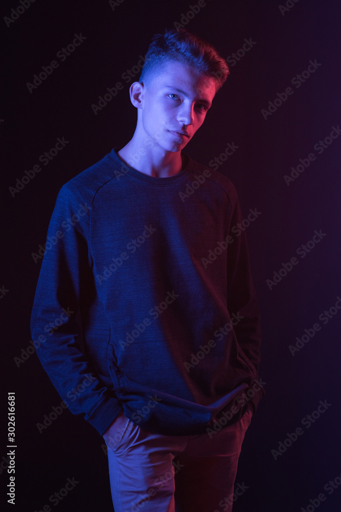 Naklejka premium Serious young guy in brown sweater in neon light