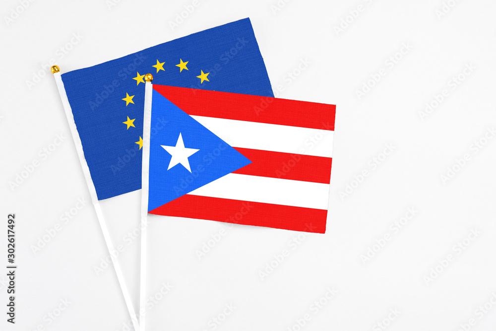 Puerto Rico and European Union stick flags on white background. High quality fabric, miniature national flag. Peaceful global concept.White floor for copy space. Puerto Rico and European Union stick flags on white background. High quality fabric, miniature national flag. Peaceful global concept.White floor for copy space.