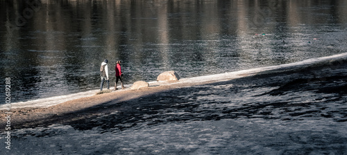 Two are walking by the winter river. photo