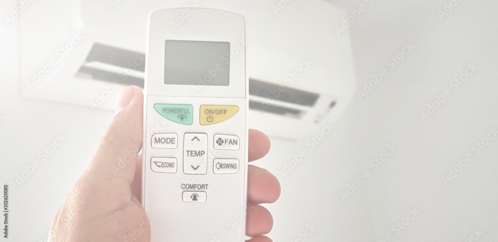 Modern airconditioner unit with a hand holding a remote. Modern airconditioner unit with a hand holding a remote.