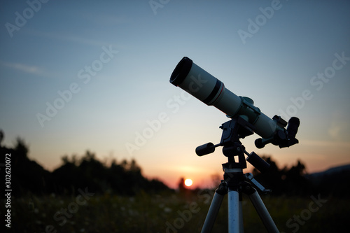 Telescope for observing the universe on a meadow outdoors.