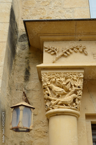 Stone pillar with zoological carving and a street lantern in the French town Saint Medard photo