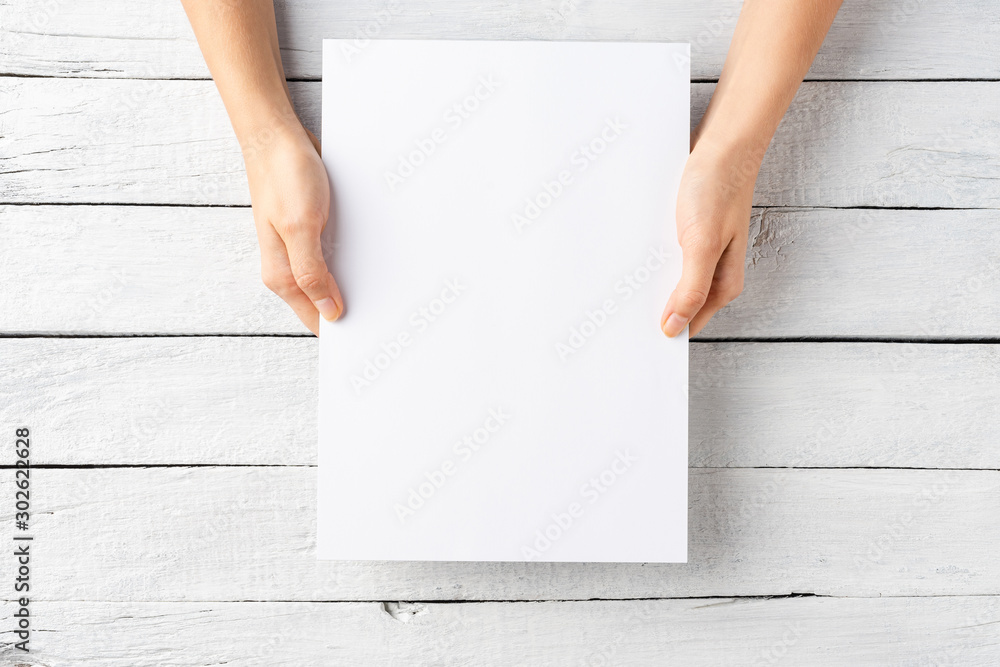 Young female hands holding paper sheet with copyspace. Top view Young female hands holding paper sheet with copyspace. Top view
