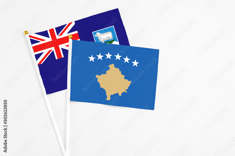 Fototapeta premium Kosovo and Falkland Islands stick flags on white background. High quality fabric, miniature national flag. Peaceful global concept.White floor for copy space.