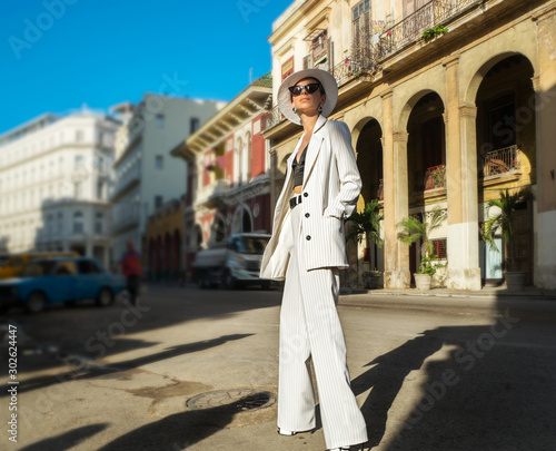 Stylish woman in a white suit and white hat on a city street. Cuba © Denis Aglichev