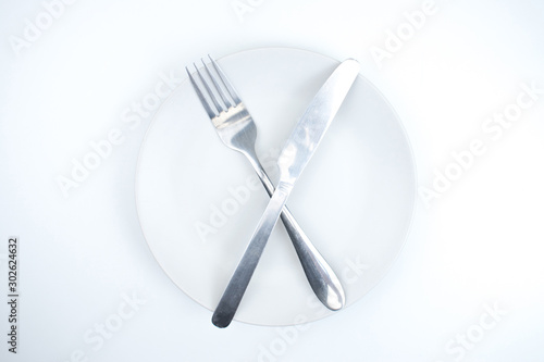 White empty plate with fork and knife on a white background.