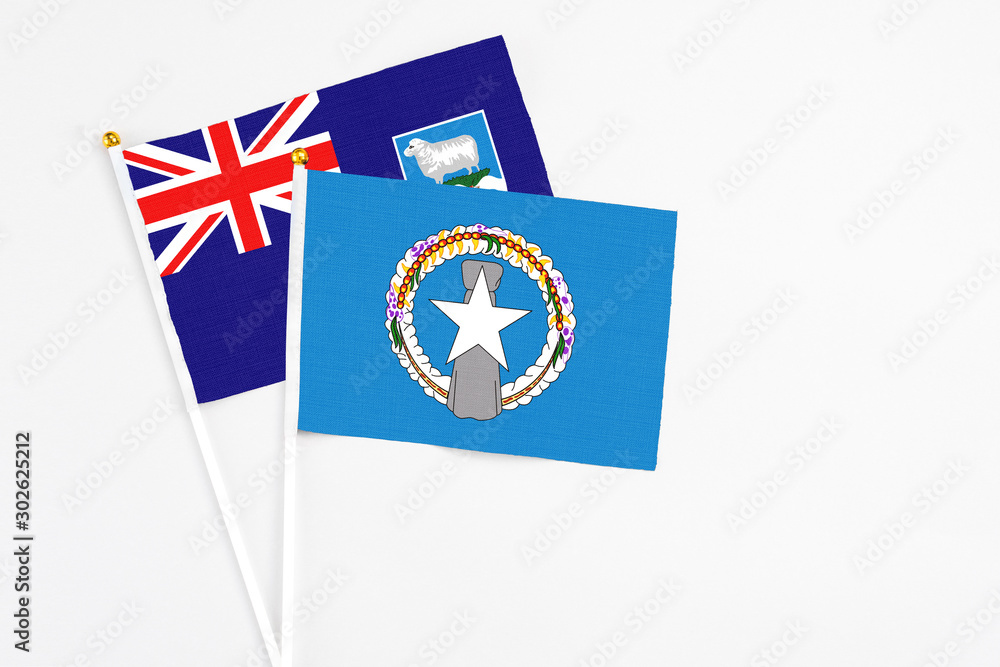 Northern Mariana Islands and Falkland Islands stick flags on white background. High quality fabric, miniature national flag. Peaceful global concept.White floor for copy space.