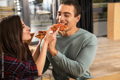 Young couple eating delicious pizza in cafe