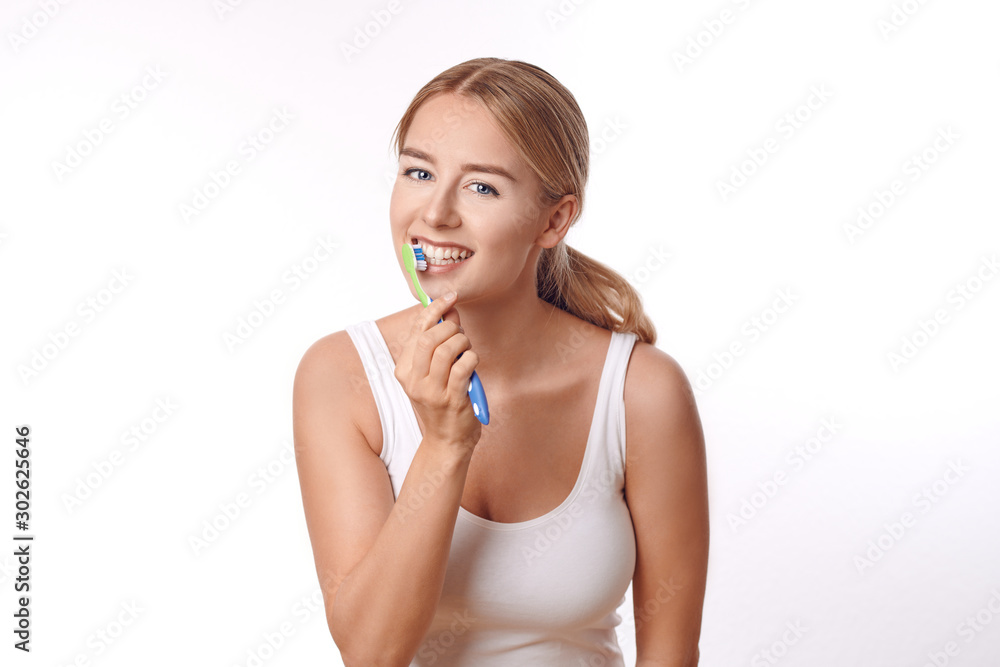 Attractive woman practicing dental hygiene brushing her teeth with a toothbrush and toothpaste to prevent tooth decay or caries , isolated on white Attractive woman practicing dental hygiene brushing her teeth with a toothbrush and toothpaste to prevent tooth decay or caries , isolated on white