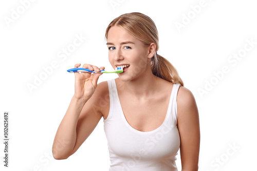 Attractive woman practicing dental hygiene brushing her teeth with a toothbrush and toothpaste to prevent tooth decay or caries , isolated on white