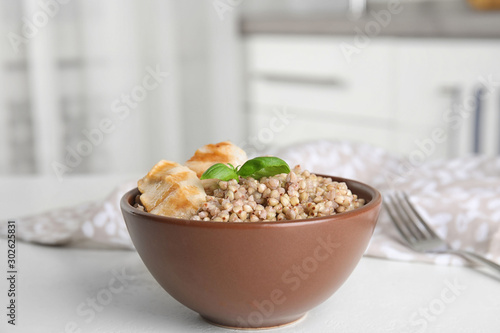 Tasty buckwheat porridge with meat on white table indoors