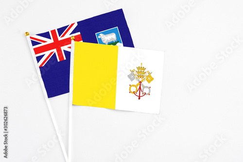Vatican City and Falkland Islands stick flags on white background. High quality fabric, miniature national flag. Peaceful global concept.White floor for copy space.