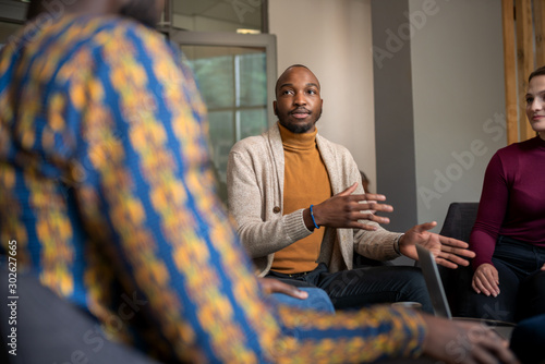 Creative black businessman talking in interview casually with fellow diverse South African coworkers