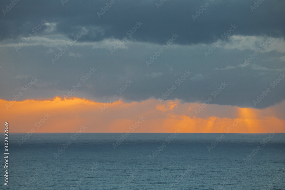 Dramatic cloudy pastel golden blue sky over the ocean on a overcast day.