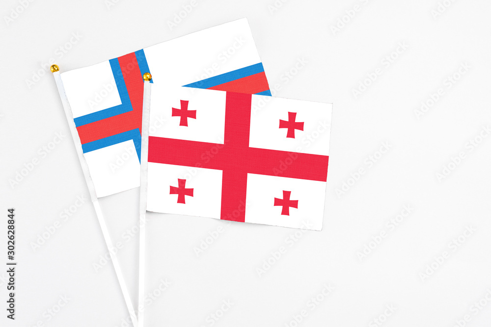 Georgia and Faroe Islands stick flags on white background. High quality fabric, miniature national flag. Peaceful global concept.White floor for copy space.