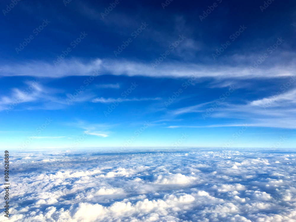 Clouds and sky as seen through window of an aircraft.Airplane wing in the blue sky above the clouds.