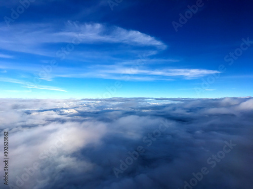 Clouds and sky as seen through window of an aircraft.Airplane wing in the blue sky above the clouds.