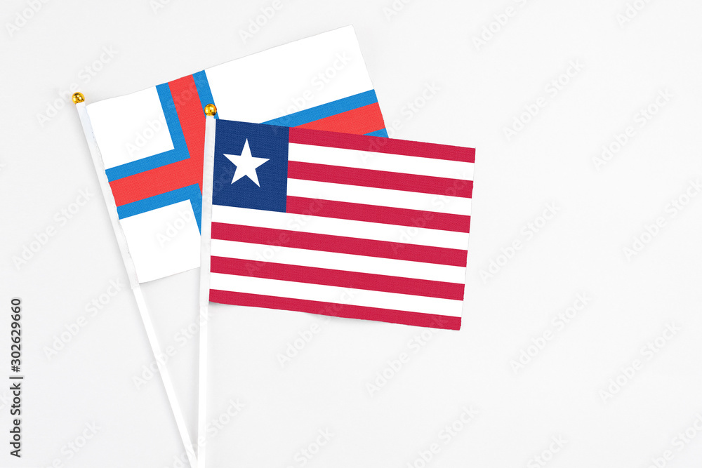 Liberia and Faroe Islands stick flags on white background. High quality fabric, miniature national flag. Peaceful global concept.White floor for copy space. Liberia and Faroe Islands stick flags on white background. High quality fabric, miniature national flag. Peaceful global concept.White floor for copy space.
