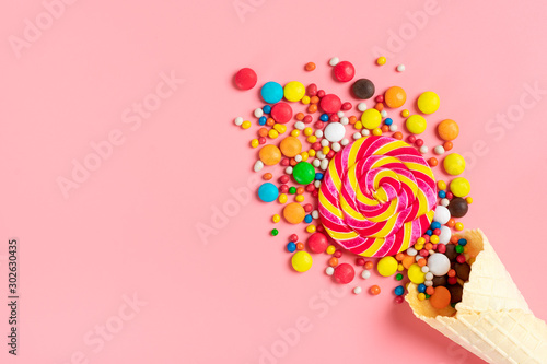 mix colorful chocolate sweets spilled out of ice cream waffle cone on pink background Flat lay Top view Place for text Holiday card Happy birthday party, Happy Valentine's day concept