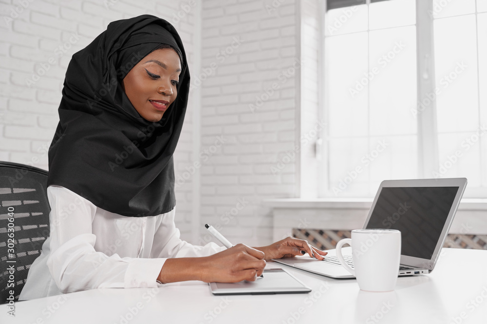 Attactive muslim woman in black hijab using computer Attactive muslim woman in black hijab using computer