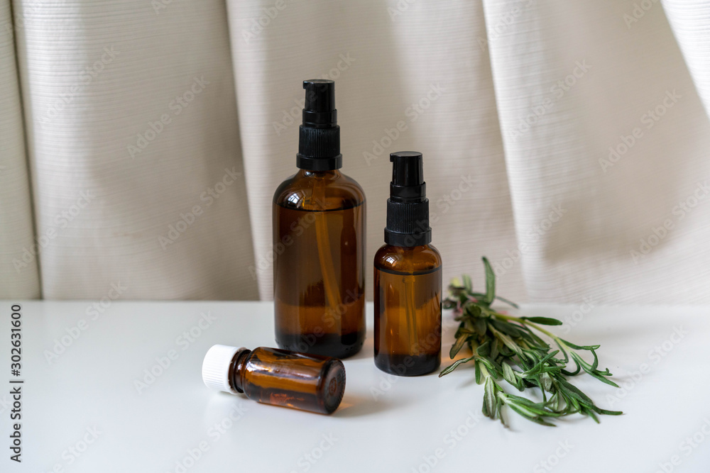 Organic products in glass bottles with fresh rosemary herb on white. Organic products in glass bottles with fresh rosemary herb on white.