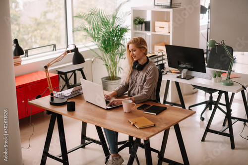 Young businesswoman in office. Beautiful woman with headphones. 