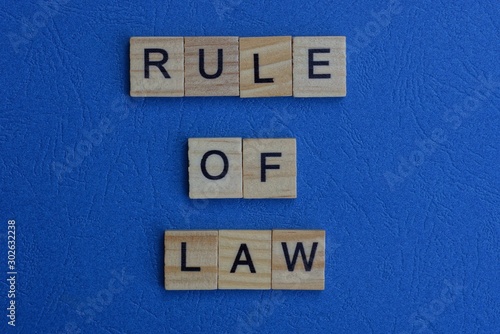 The phrase rule of law of brown wooden letters lies on a blue table
