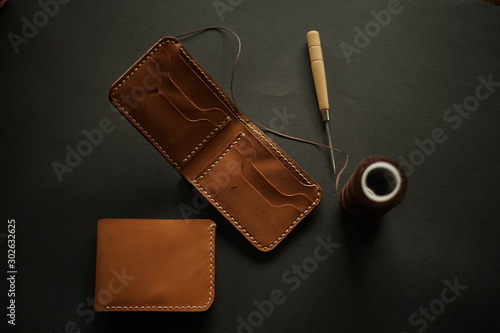 brown leather wallet with needle and a thread, hand made leather works concept. Flatlays imagery