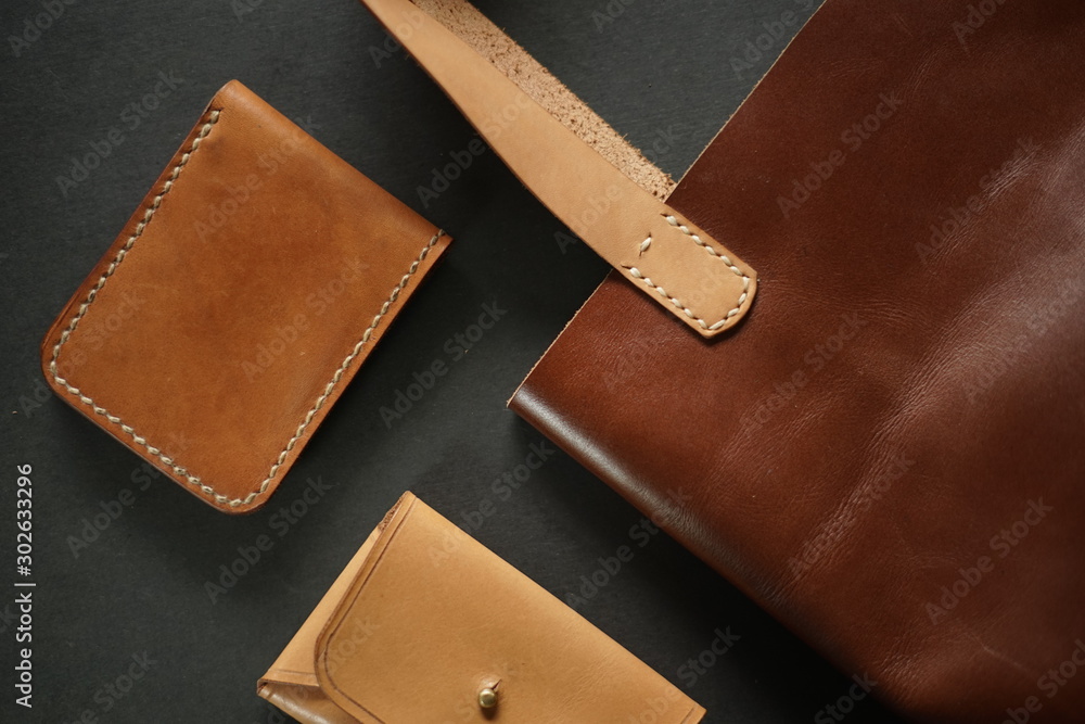 Top view of leather craft, handcrafted leather wallet and totebag. Luxury design in black background. Top view of leather craft, handcrafted leather wallet and totebag. Luxury design in black background.