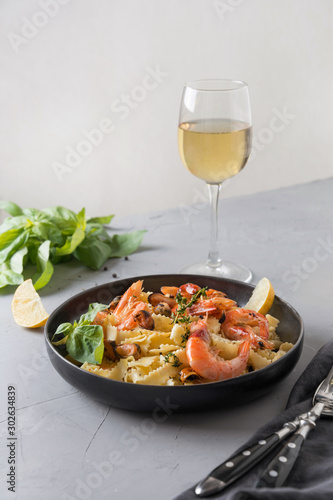 Pasta reginelle with seafood, shrimps, mussels in black plate on gray stone table, close up. Traditional dish in Italian restaurant.