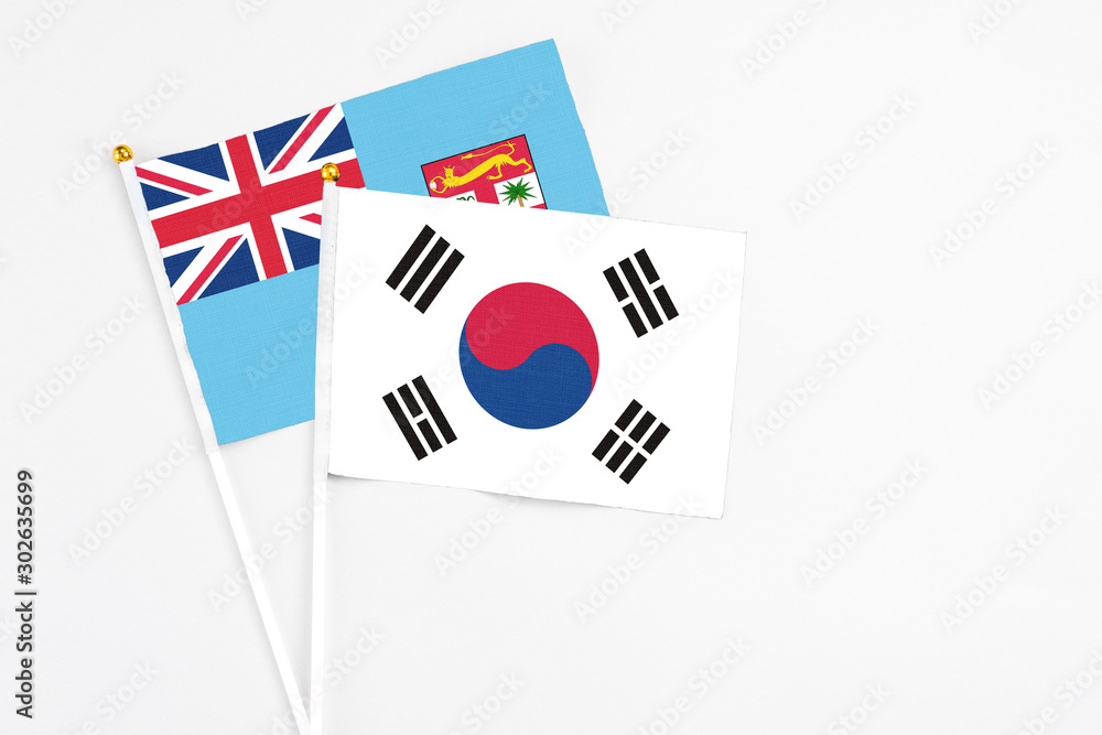 South Korea and Fiji stick flags on white background. High quality fabric, miniature national flag. Peaceful global concept.White floor for copy space.