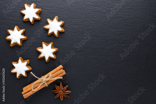 star cookies on black background with cinnamon, anise and copy space