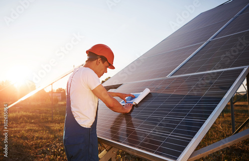 Beautiful sunlight. Male worker in blue uniform outdoors with solar batteries