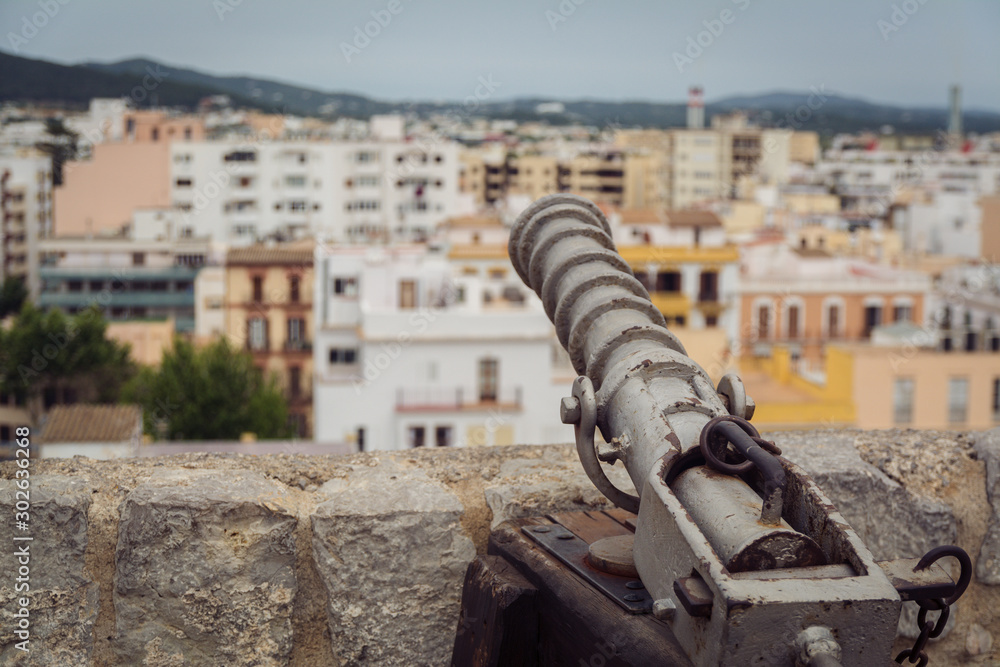 View from Ibiza town Eivissa from the town fort castle with an old medieval protection canon in foreground old white and yellow Mediterranean buildings top view of city View from Ibiza town Eivissa from the town fort castle with an old medieval protection canon in foreground old white and yellow Mediterranean buildings top view of city