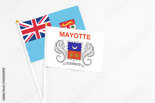 Mayotte and Fiji stick flags on white background. High quality fabric, miniature national flag. Peaceful global concept.White floor for copy space.