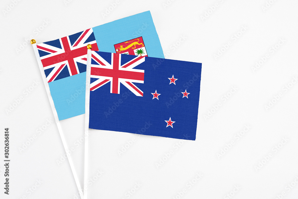 Fototapeta premium New Zealand and Fiji stick flags on white background. High quality fabric, miniature national flag. Peaceful global concept.White floor for copy space.