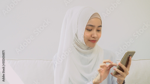 Muslim woman in hijab is buying online with a credit card and smartphone at home