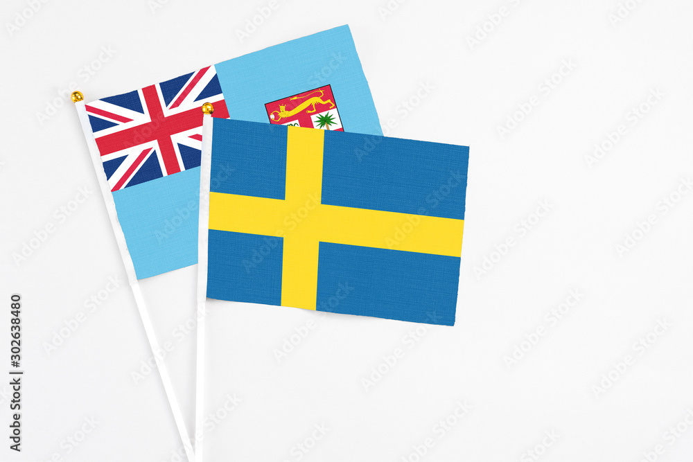 Sweden and Fiji stick flags on white background. High quality fabric, miniature national flag. Peaceful global concept.White floor for copy space.